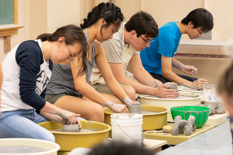 Students creating ceramics/pottery on throwing wheels